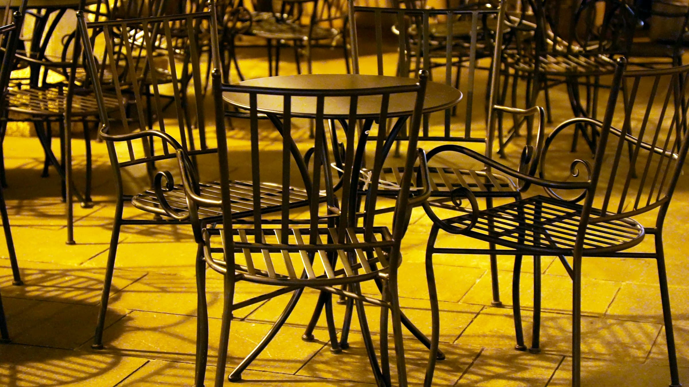 Lege stoelen en tafeltjes op een terras in goudgeel licht