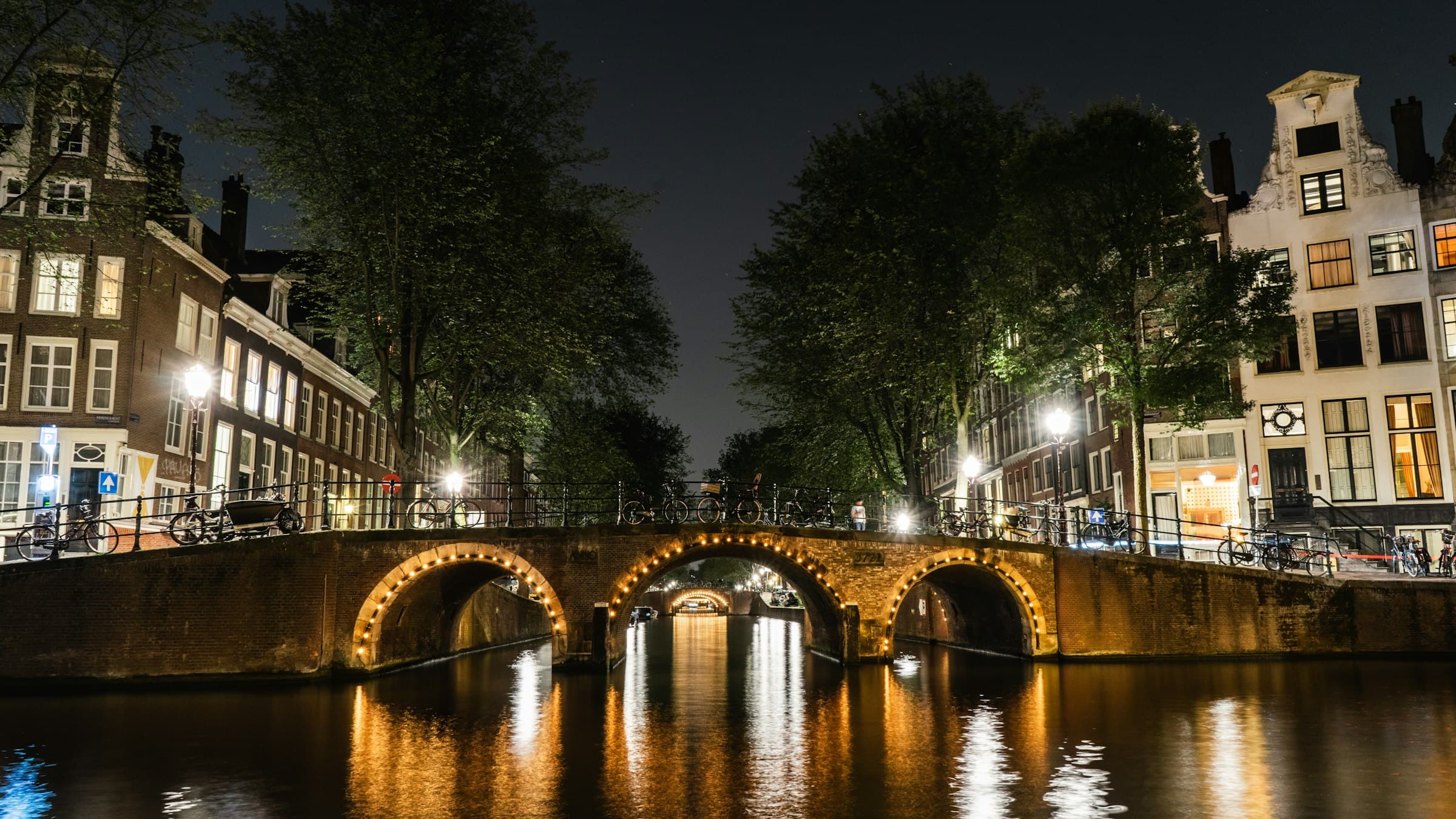 Een Amsterdamse gracht met verlichte bruggen in de schemering