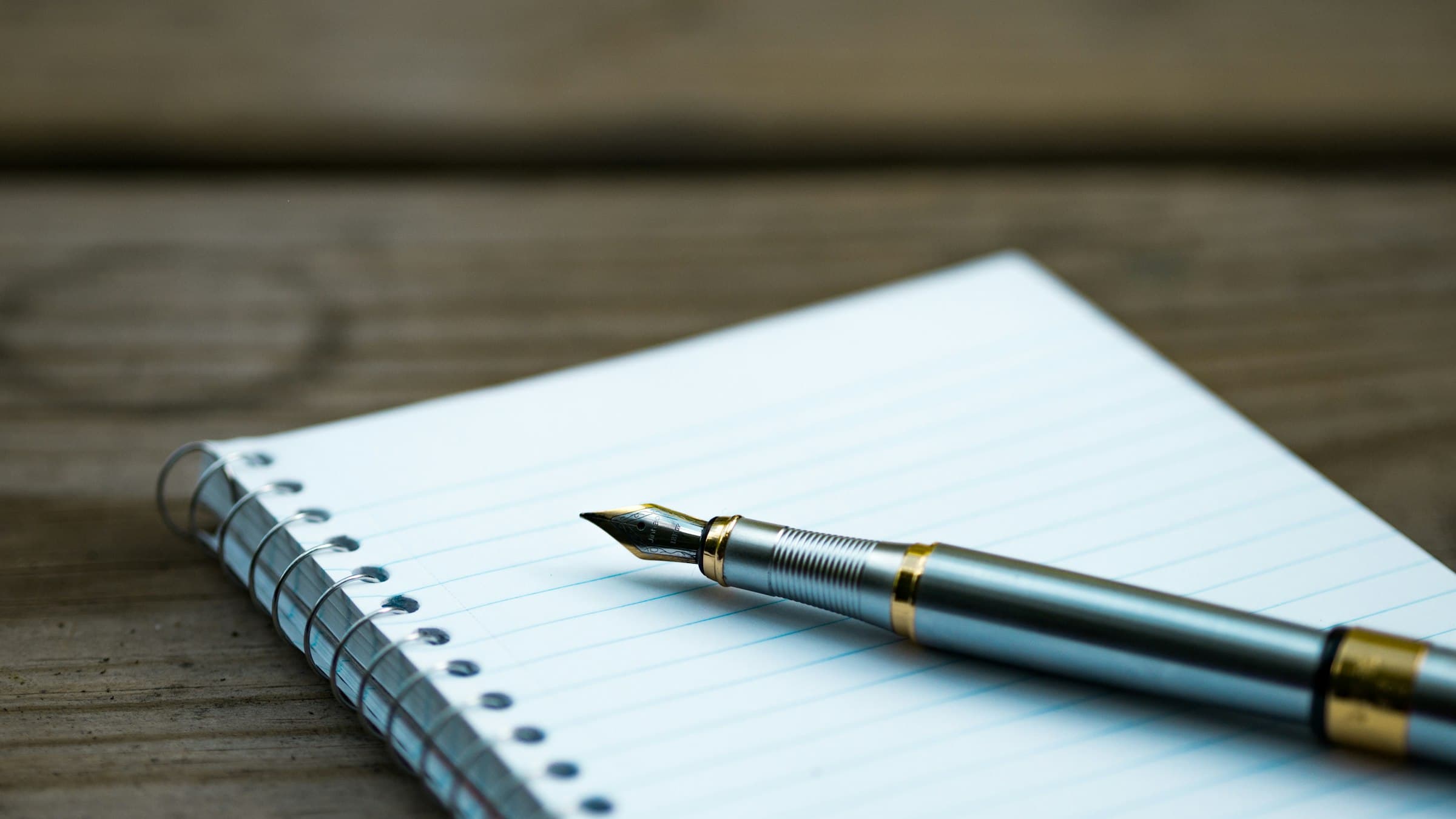 An open notepad with a fountain pen on a wooden table