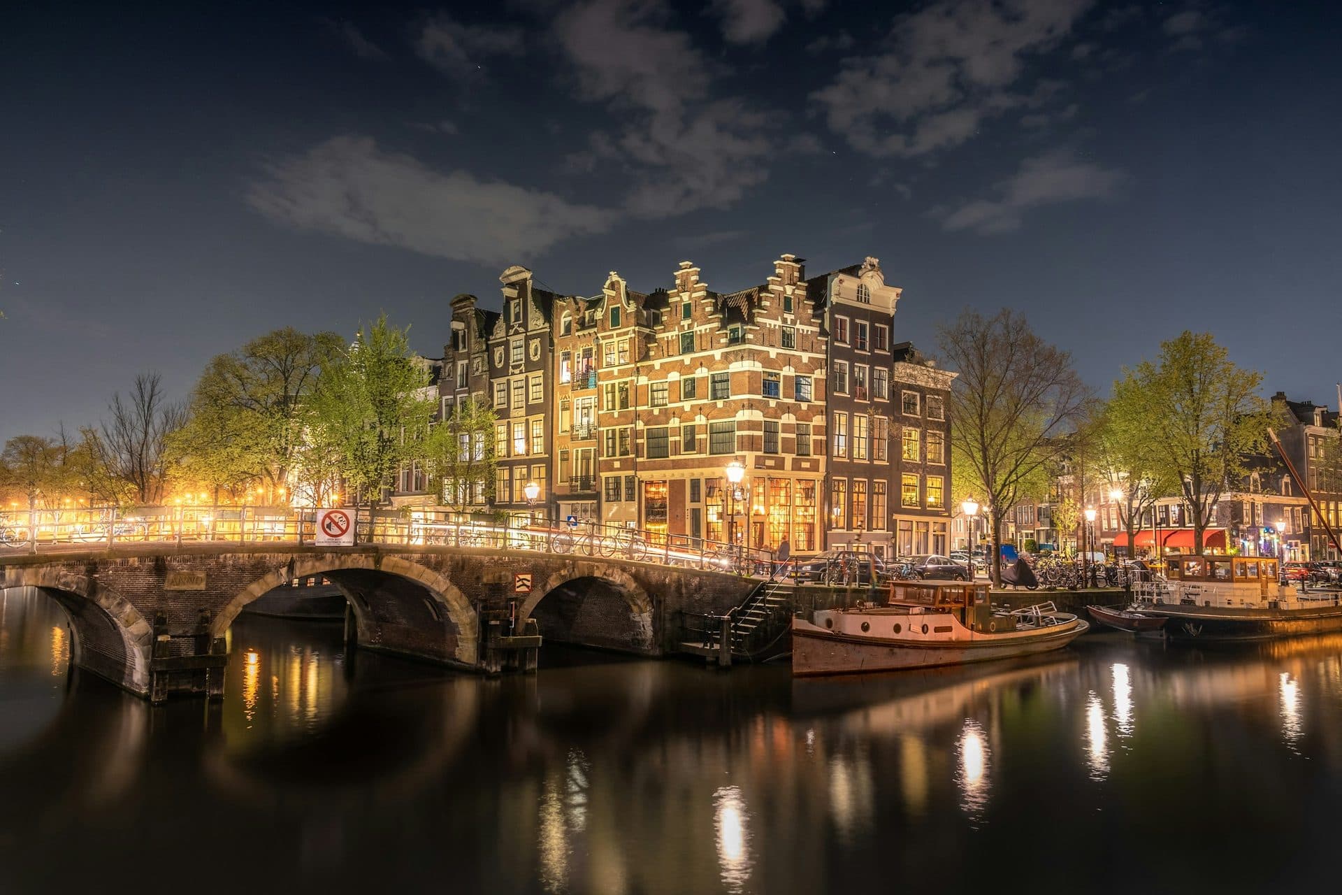Verlichte grachtenpanden aan een Amsterdamse gracht in de avond