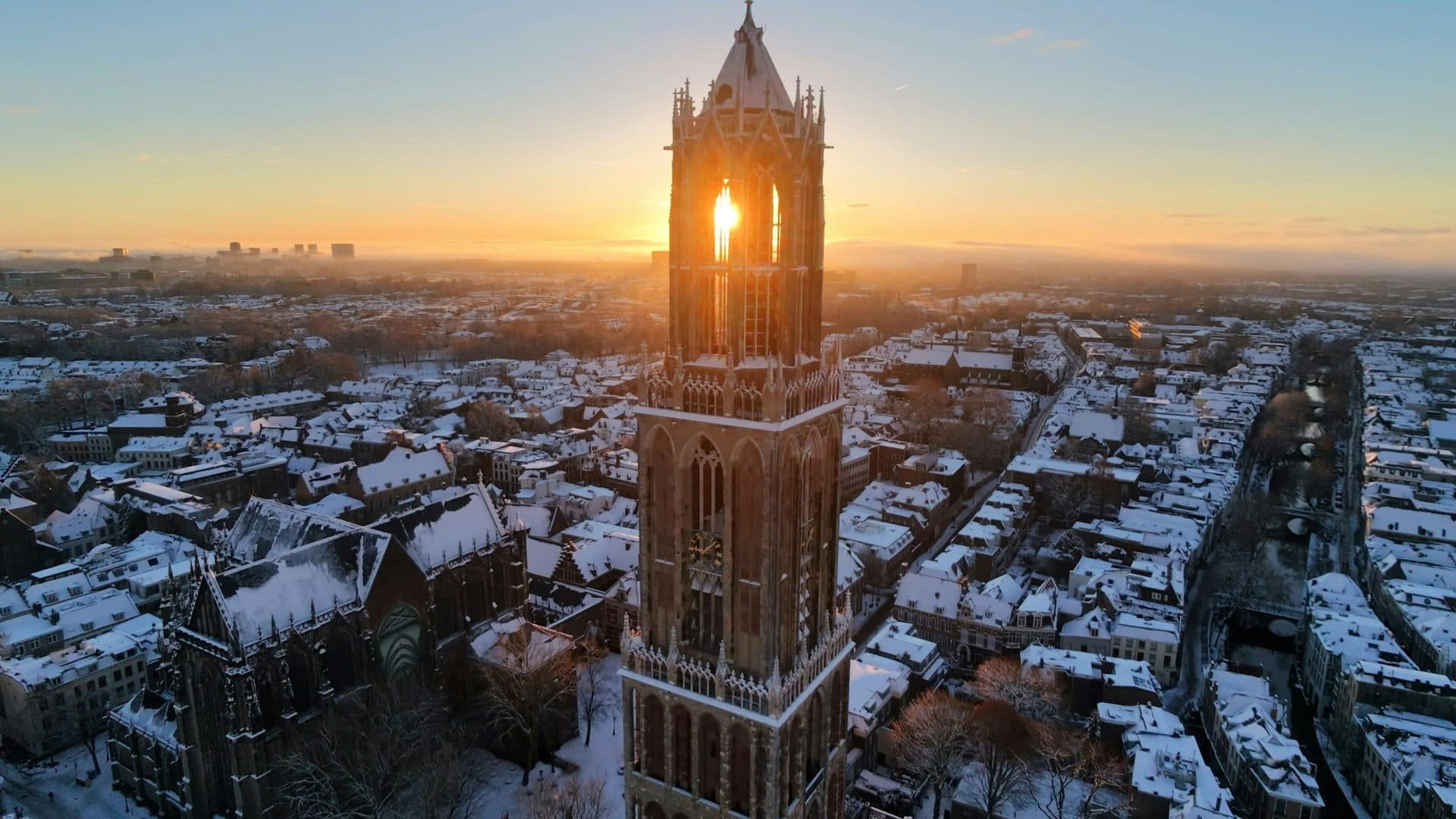 De Domtoren boven het besneeuwde Utrecht bij zonsopkomst