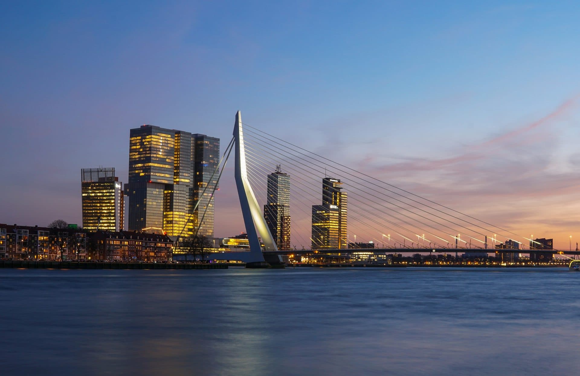Illuminated towers and the Erasmus Bridge on the Maas at dusk